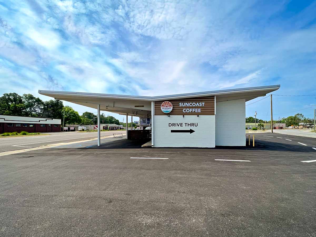 Outside of Suncoast Coffee, a small white building with medium wood accents in a mid-century style